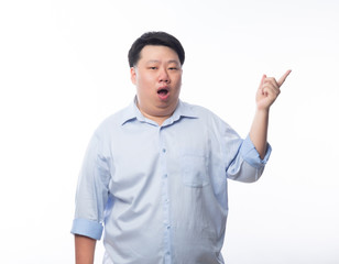 Asian Fat Man in blue shirt pointing to copyspace with doubts face isolated on white background.