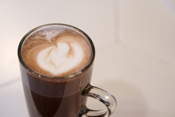 closeup hot cocoa or chocolate and mocha with milk froth in clear glass cup on table in cafe or restaurant and coffee shop for breakfast or snack and morning drink background on vintage warm white