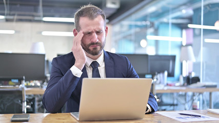 The Tired Young Businessman having Headache in Office