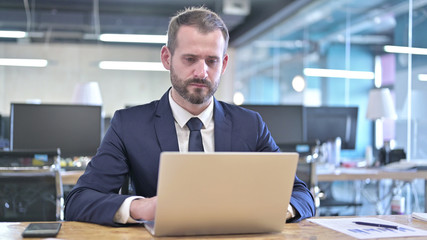 The Ambitious Businessman working on Laptop on Office Desk