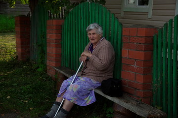 Portrait of a Russian pensioner resting on a bench near the house.