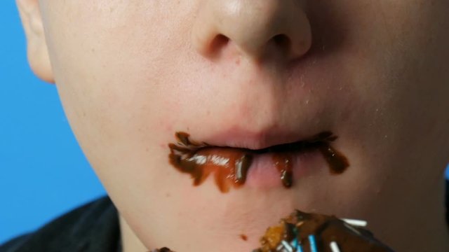 Teen boy dirty mouth eating chocolate fat donut. Harmful sweet, junk food