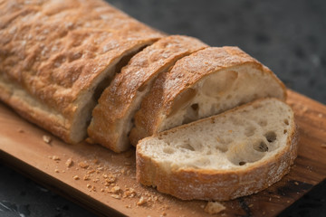 sliced freshly baked ciabatta bread on olive board