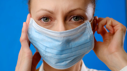 closeup portrait of a woman wearing protective mask. Concept of health and safety life, coronavirus, virus protection, pandemic. blue background 