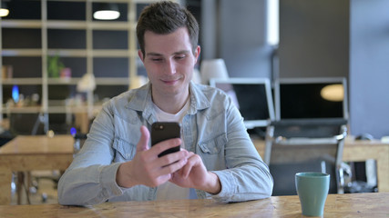 The Attractive Young Designer using Smartphone in Modern Office