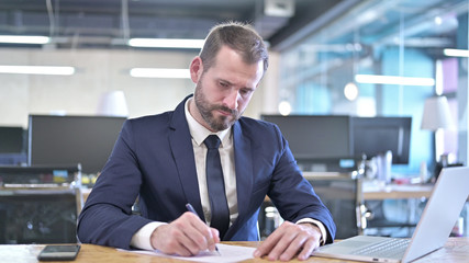 Fototapeta na wymiar The Young Businessman writing Documents on Office Desk