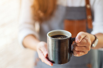 A waitress holding and serving a cup of hot coffee in cafe