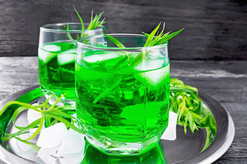 Lemonade Tarragon with ice in two glasses on wooden board