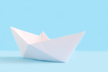 White paper handmade origami boat on the blue background. Cruise ship travel theme.