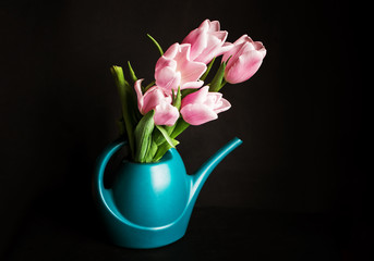 A beautiful bouquet of pink tulips in a water can on a dark background. A place for text.