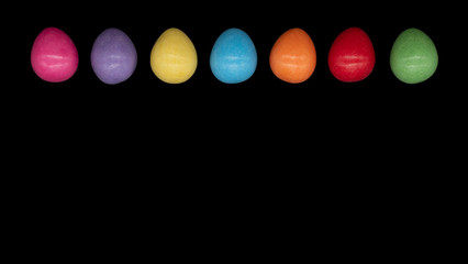 Bright colourful candy Easter eggs arranged on a plain black background with copy space