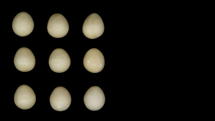 Pale creamy white chocolate Easter eggs on a plain black background