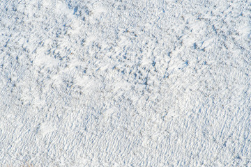 Background with snow tundra with snow-covered grass and bushes shot from above.