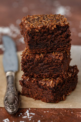 Brownies. Fresh baked homemade vegan brownie with ground coconut and chocolate slices cut in square servings . Delicious American dessert close up. Selective focus