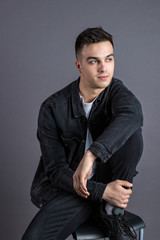 Fototapeta premium Young serious man posing in studio. Gray background