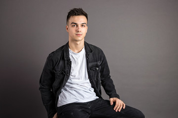 Young serious man posing in studio. Gray background