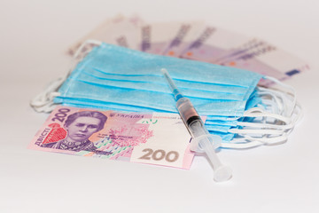 Protective medical mask, syringe vaccine and Ukrainian hryvnia. Expensive medicine concept.