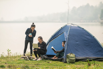 Group of friends on a camping trip relaxing by their tent