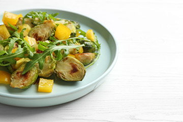 Delicious salad with roasted Brussels sprouts on white wooden table, closeup