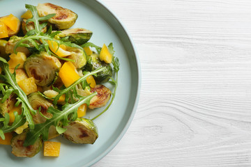 Delicious salad with roasted Brussels sprouts on white wooden table, top view. Space for text