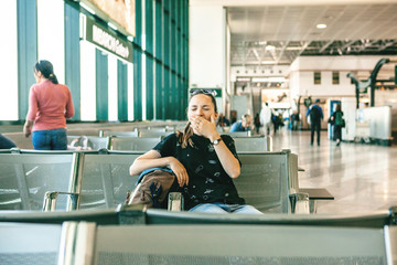 Tired girl tourist or student yawns at the airport while waiting for a flight. Flight delay. Sleepy...