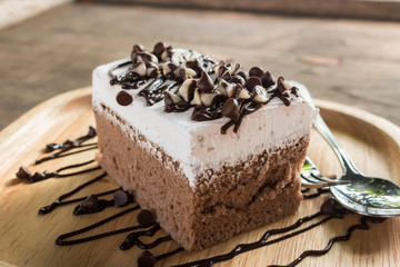 Chocolate chip cake sprinkles chocolate on top in a wooden tray, on a wood table is the background. Close up photography.