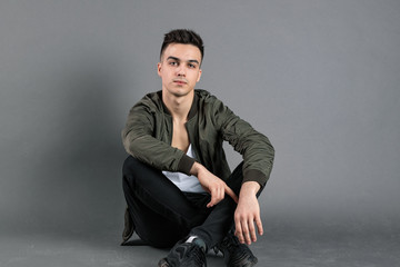 Young serious man posing in studio. Gray background