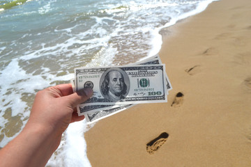 Girl holding money bill of 300 dollars on background of sea oceans
