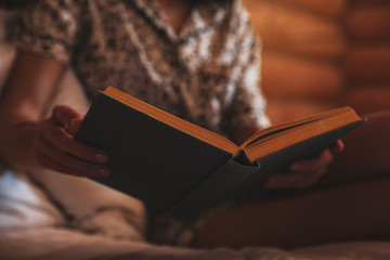 Woman reading book on bed at home, closeup