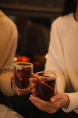 Couple with tasty mulled wine near fireplace indoors, closeup