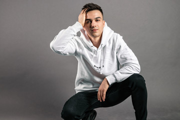 Young serious man posing in studio. Gray background