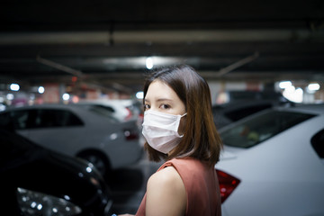 Fototapeta na wymiar covid-19 spreading outbreak. Woman in medical protective mask at a parking lot..Fear of coronavirus.