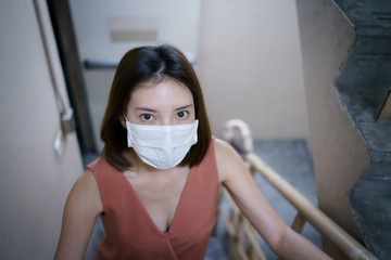 Fototapeta na wymiar covid-19 spreading outbreak. Woman in medical protective mask at stairwell fire escape in a building. Fear of coronavirus.