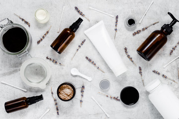 Delicate skin care cosmetic feminine flatlay. Top view Creative composition of face cream ,glass bottles and jars with cosmetic, cotton swabs and dried lavender on textured marble background