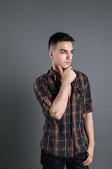 Young serious man posing in studio. Gray background