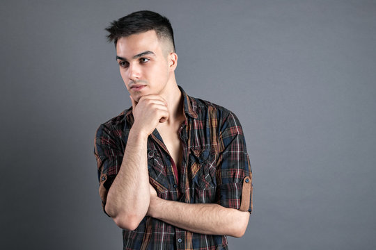 Young serious man posing in studio. Gray background