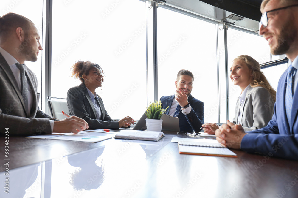 Sticker Group of young modern people in formalwear smiling and discussing something while working in the modern office