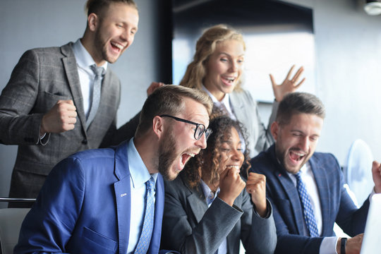 Happy Business People Laugh Near Laptop In The Office. Successful Team Coworkers Joke And Have Fun Together At Work.