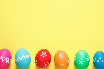 Colorful Easter eggs on yellow background, flat lay. Space for text