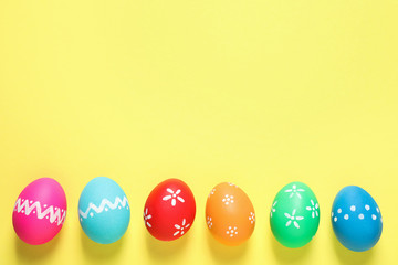 Colorful Easter eggs on yellow background, flat lay. Space for text
