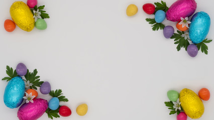 Bright coloured chocolate eggs in foil and small candy eggs arranged with leaves and white flowers on a scrunched white paper background with copy space