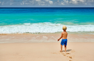 Three year old toddler boy walking on beach