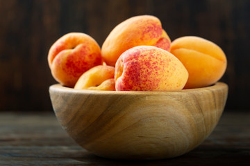 Ripe apricots in a wooden bowl.