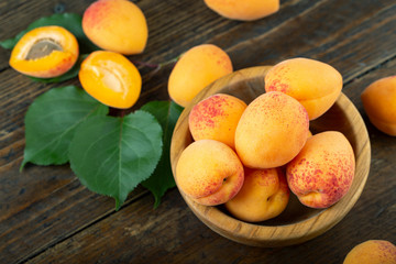 Naklejka na ściany i meble Delicious ripe apricots in a wooden bowl on the table close-up.