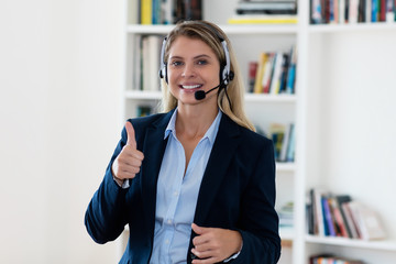 Laughing blond call center female agent with headphones