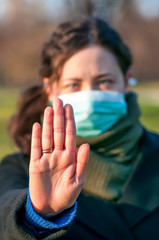 Portrait of a caucasian brunette woman in park in protective medical mask on face protection for spreading of disease virus SARS-CoV-2, Coronavirus, COVID-19