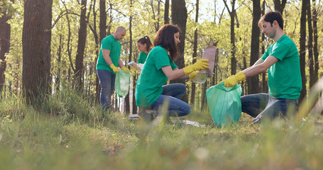 Volunteers in green T-shirts clean up the plastic trash in the park.