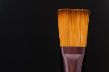 single makeup brush on black background macro view