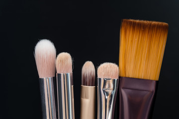 Set of makeup brushes on black background view