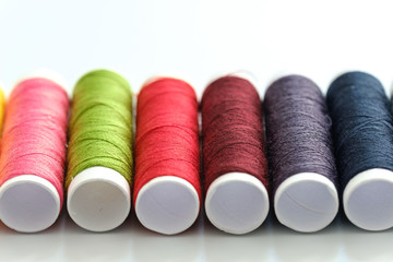 Close up macro view of colorful yarn reels on white background